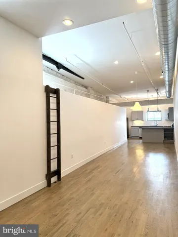 an empty room with kitchen view and windows