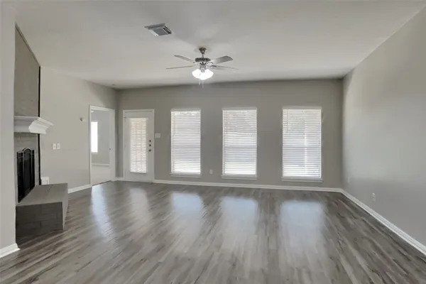 a view of an empty room with a window and wooden floor