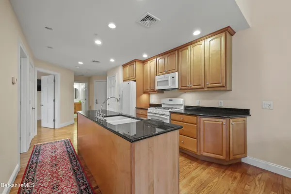 a kitchen with granite countertop sink stove and cabinets