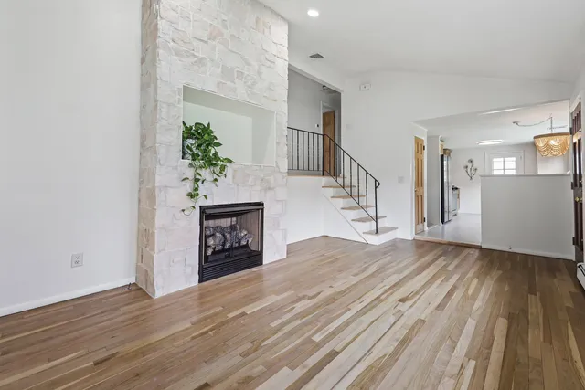 a view of an empty room with wooden floor and a fireplace