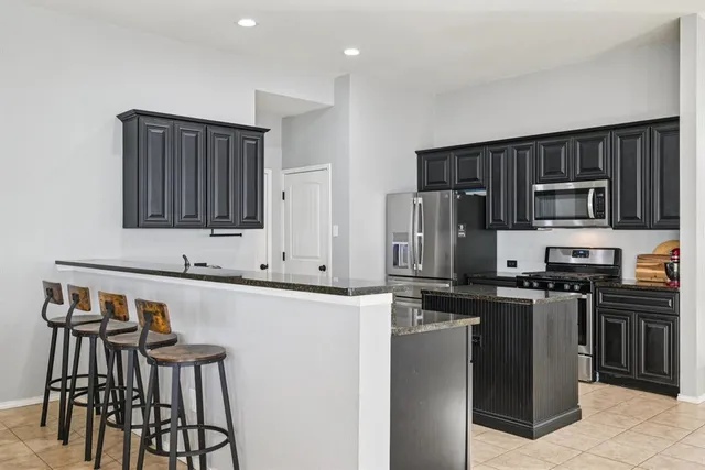 a kitchen with stainless steel appliances granite countertop a stove a sink dishwasher a microwave oven and a refrigerator with wooden floor