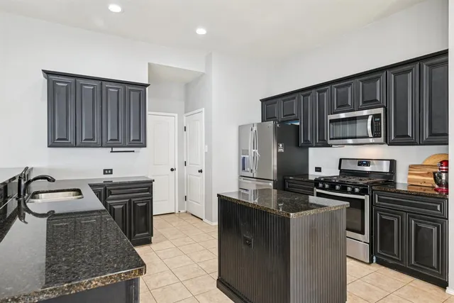 a kitchen with granite countertop a sink stove and refrigerator