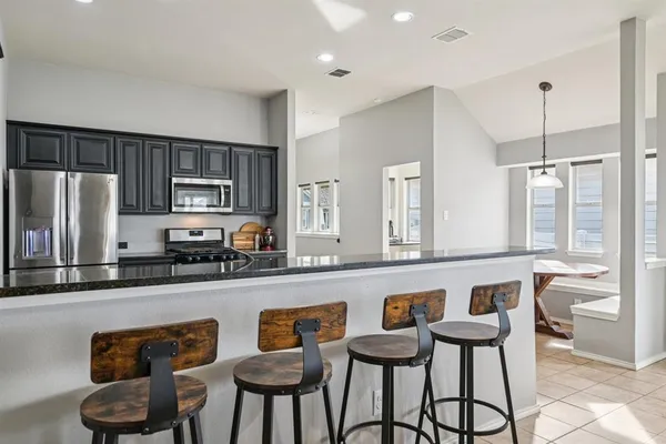 a kitchen with stainless steel appliances granite countertop a sink a stove a refrigerator cabinets and chairs