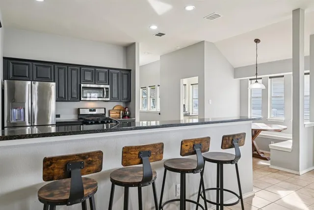 a kitchen with stainless steel appliances granite countertop a sink a stove a refrigerator cabinets and chairs