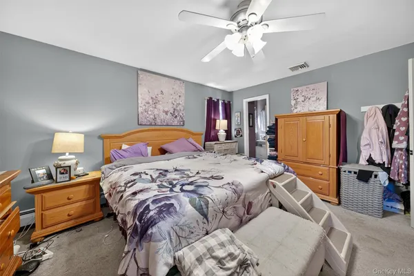 a bedroom with a bed and a flat tv screen on dresser