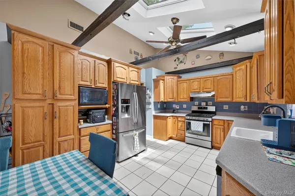 a kitchen with stainless steel appliances granite countertop a stove top oven a sink dishwasher a dining table and chairs with wooden floor