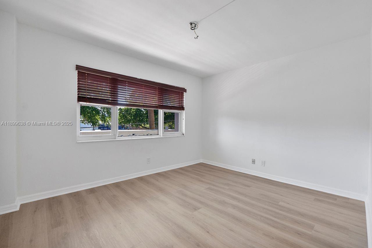 3111 Northeast 51st Street, Unit 202C Fort Lauderdale, FL 33308 - Photo 14 of 46 a view of an empty room with wooden floor and a window