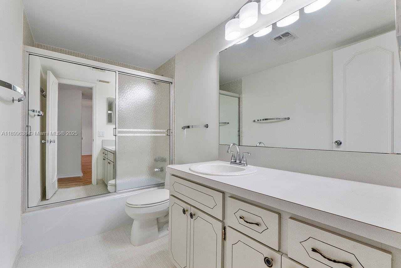 3111 Northeast 51st Street, Unit 202C Fort Lauderdale, FL 33308 - Photo 15 of 46 a spacious bathroom with a granite countertop sink a toilet and a mirror