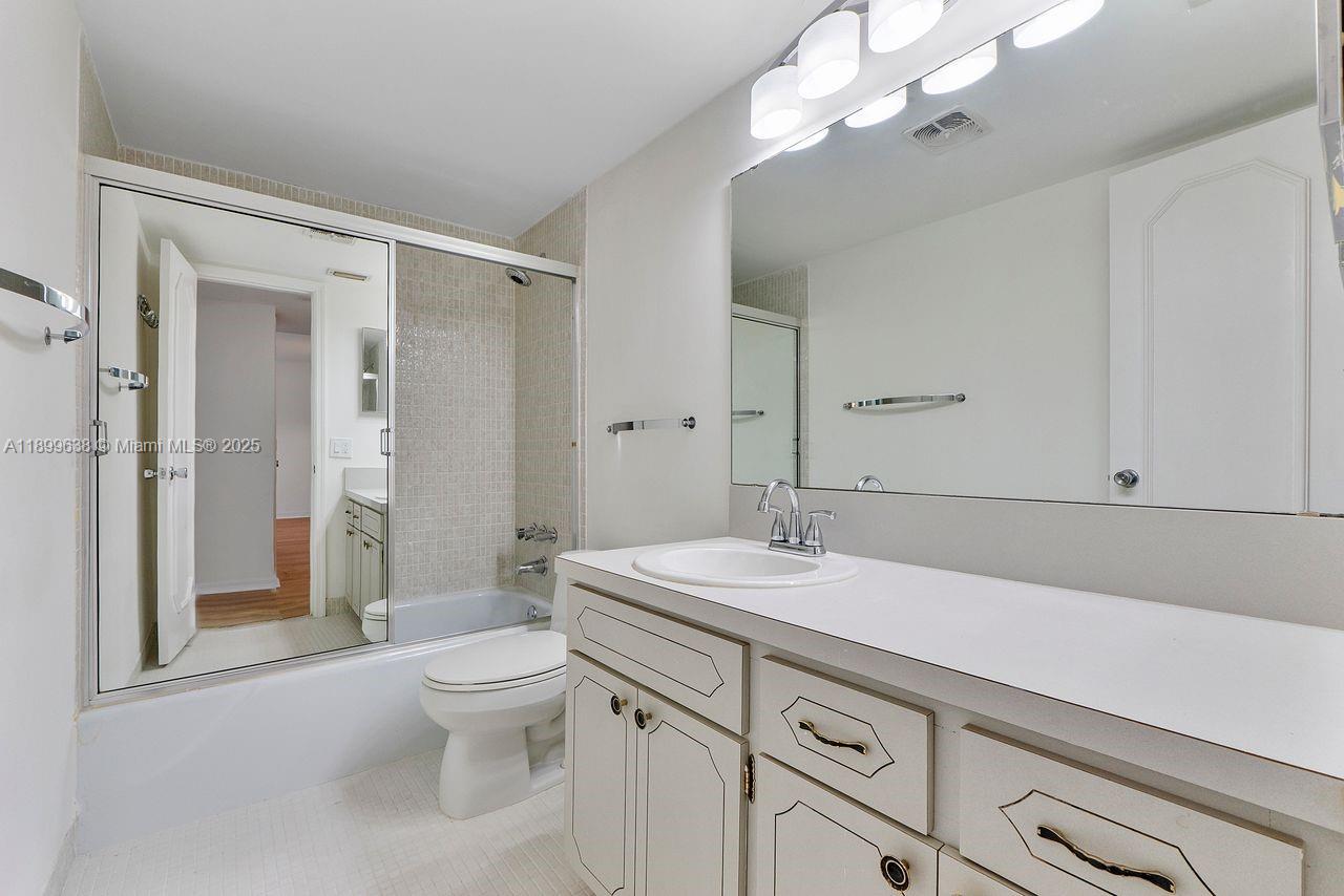 3111 Northeast 51st Street, Unit 202C Fort Lauderdale, FL 33308 - Photo 16 of 46 a bathroom with a sink a toilet and a large mirror