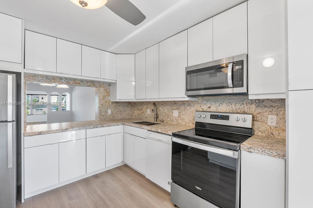 3111 Northeast 51st Street, Unit 202C Fort Lauderdale, FL 33308 - Photo 18 of 46 a kitchen with granite countertop white cabinets stainless steel appliances and a sink