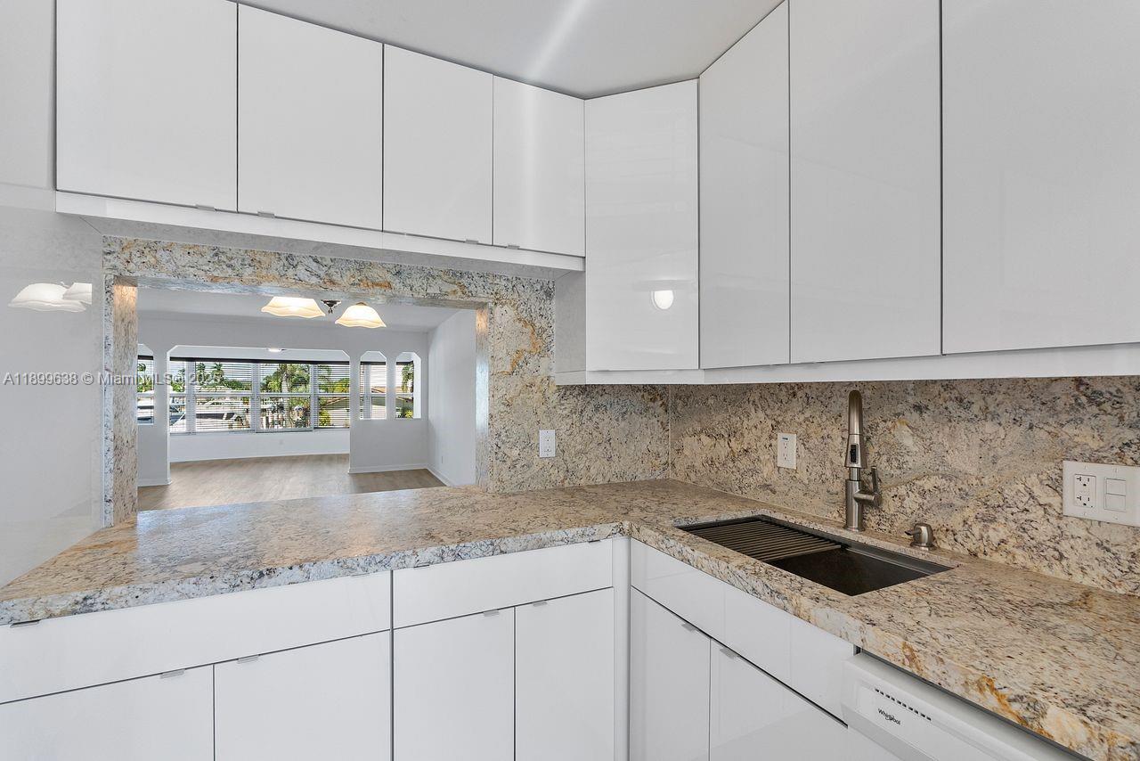 3111 Northeast 51st Street, Unit 202C Fort Lauderdale, FL 33308 - Photo 21 of 46 a kitchen with granite countertop white cabinets and a white stainless steel appliances