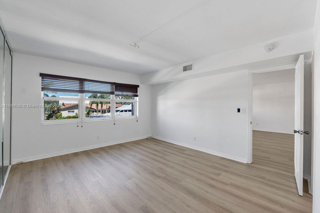 3111 Northeast 51st Street, Unit 202C Fort Lauderdale, FL 33308 - Photo 27 of 46 a view of an empty room with a window and wooden floor