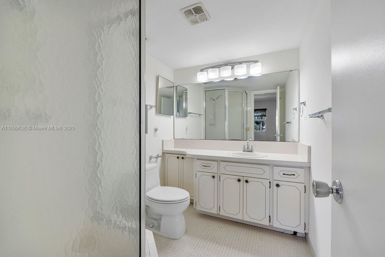3111 Northeast 51st Street, Unit 202C Fort Lauderdale, FL 33308 - Photo 28 of 46 a spacious bathroom with a granite countertop sink a toilet and a mirror