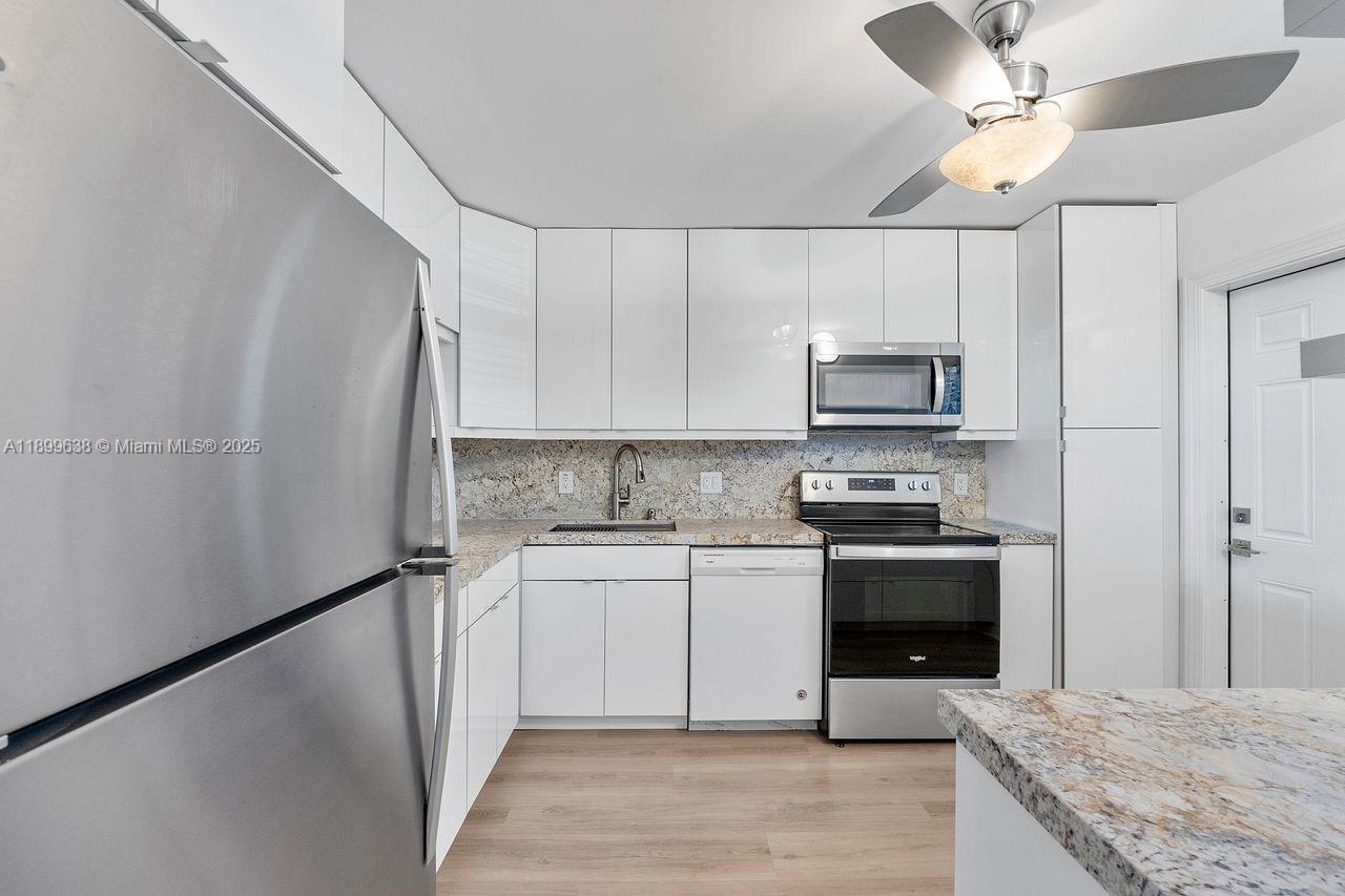 3111 Northeast 51st Street, Unit 202C Fort Lauderdale, FL 33308 - Photo 9 of 46 a kitchen with stainless steel appliances granite countertop a refrigerator a stove a sink and a microwave