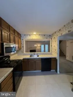 a large kitchen with kitchen island granite countertop a stove top oven a sink a counter space and cabinets