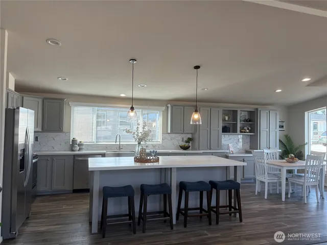 a kitchen with granite countertop a dining table chairs and wooden floor