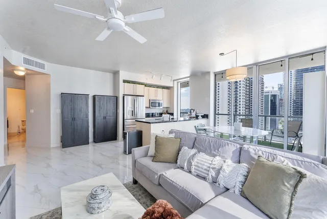 a living room with furniture and a large window with kitchen view
