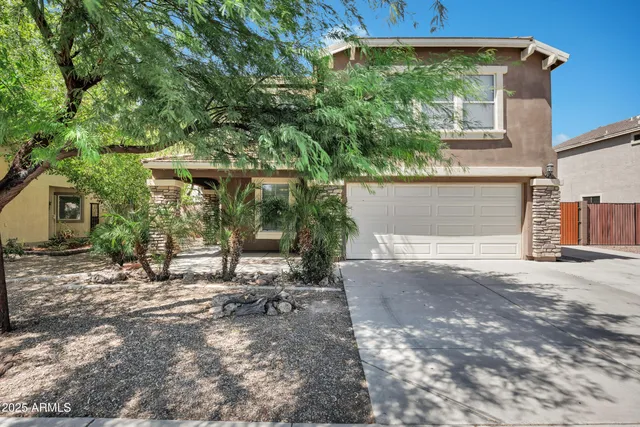 a view of a house with a yard and large tree