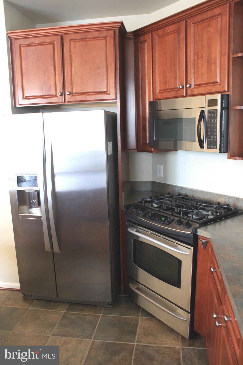 8378 Tillett Loop Manassas, VA 20110 - Photo 3 of 24 a kitchen with stainless steel appliances granite countertop a refrigerator a stove and a sink with wooden cabinets
