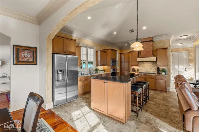 a kitchen with stainless steel appliances granite countertop a refrigerator a oven a sink a stove and a dining table with wooden floor