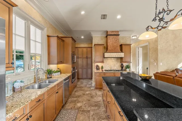 a large kitchen with kitchen island granite countertop a large counter top appliances a sink and a large window