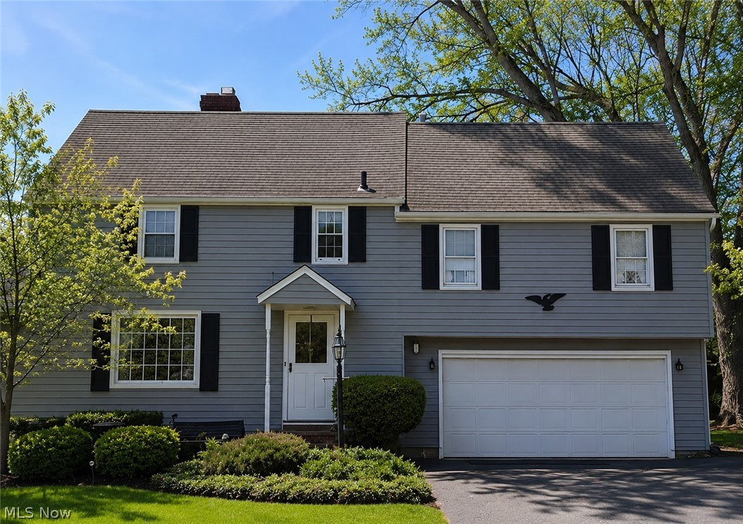 Traditional residence featuring gray siding, a prominent two-car garage, and a covered entry porch
