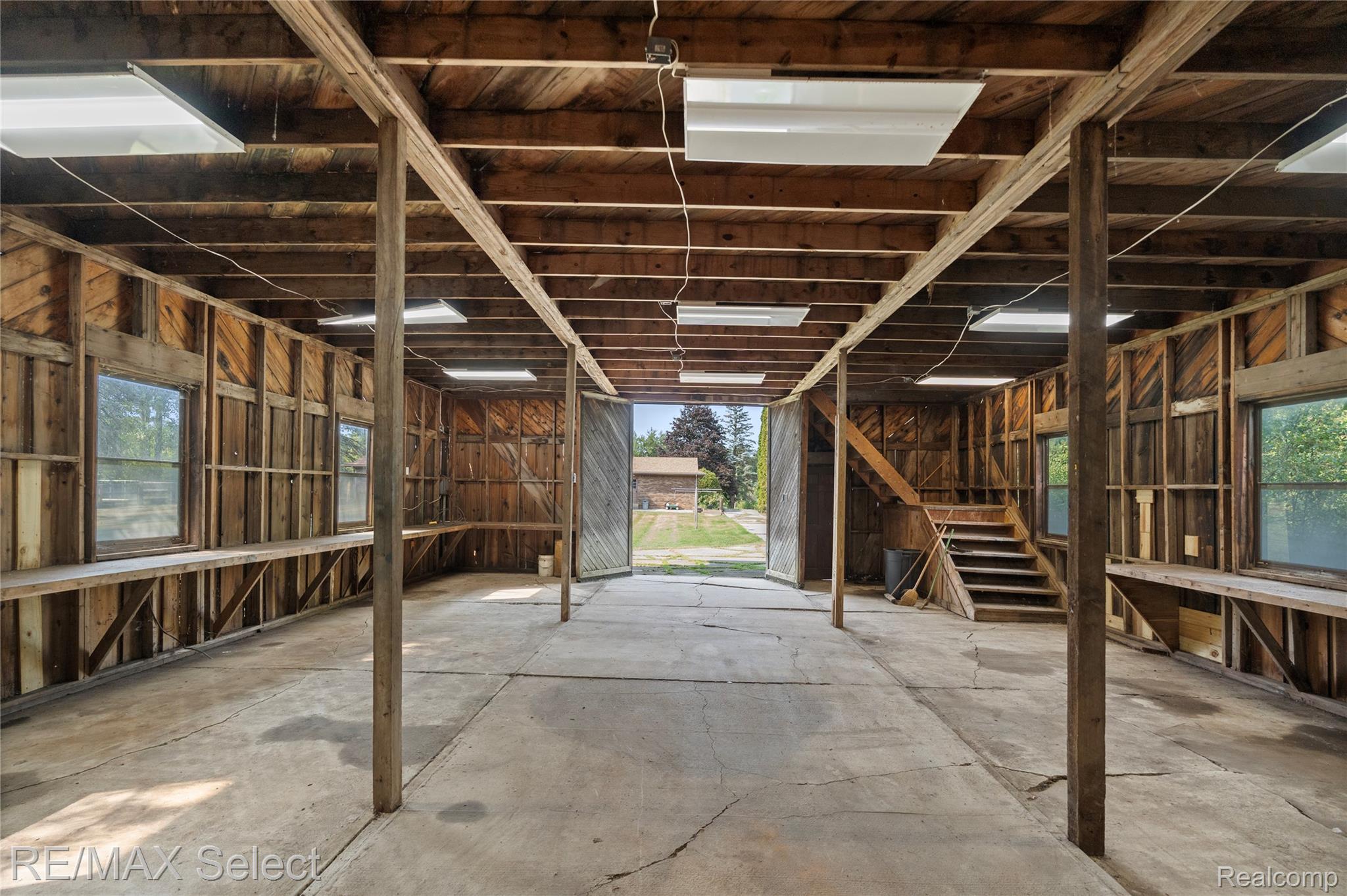 11080 Lapeer Road Davison, MI 48423 - Photo 60 of 64 Spacious industrial-style interior featuring exposed wooden beam ceiling structure, concrete flooring, steel support columns, and abundant natural light from clerestory windows