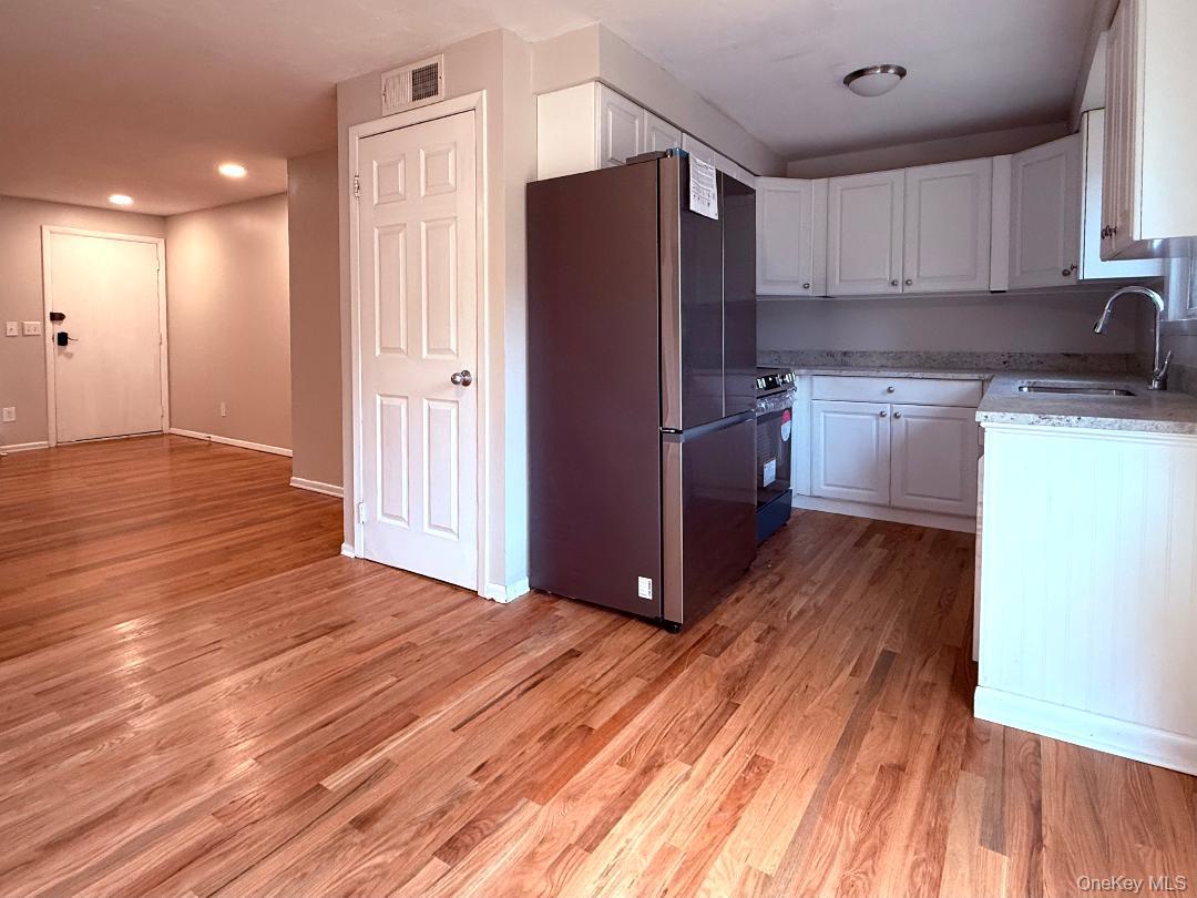200 Belvedere Road Beacon, NY 12508 - Photo 2 of 23 Kitchen featuring range with electric stovetop, sink, white cabinets, light hardwood / wood-style floors, and stainless steel refrigerator