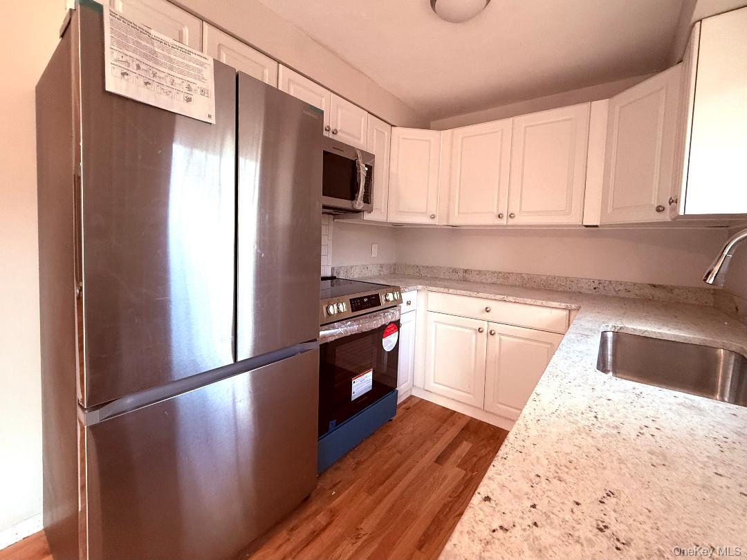 200 Belvedere Road Beacon, NY 12508 - Photo 4 of 23 Kitchen featuring appliances with stainless steel finishes, sink, white cabinets, light stone countertops, and light hardwood / wood-style floors