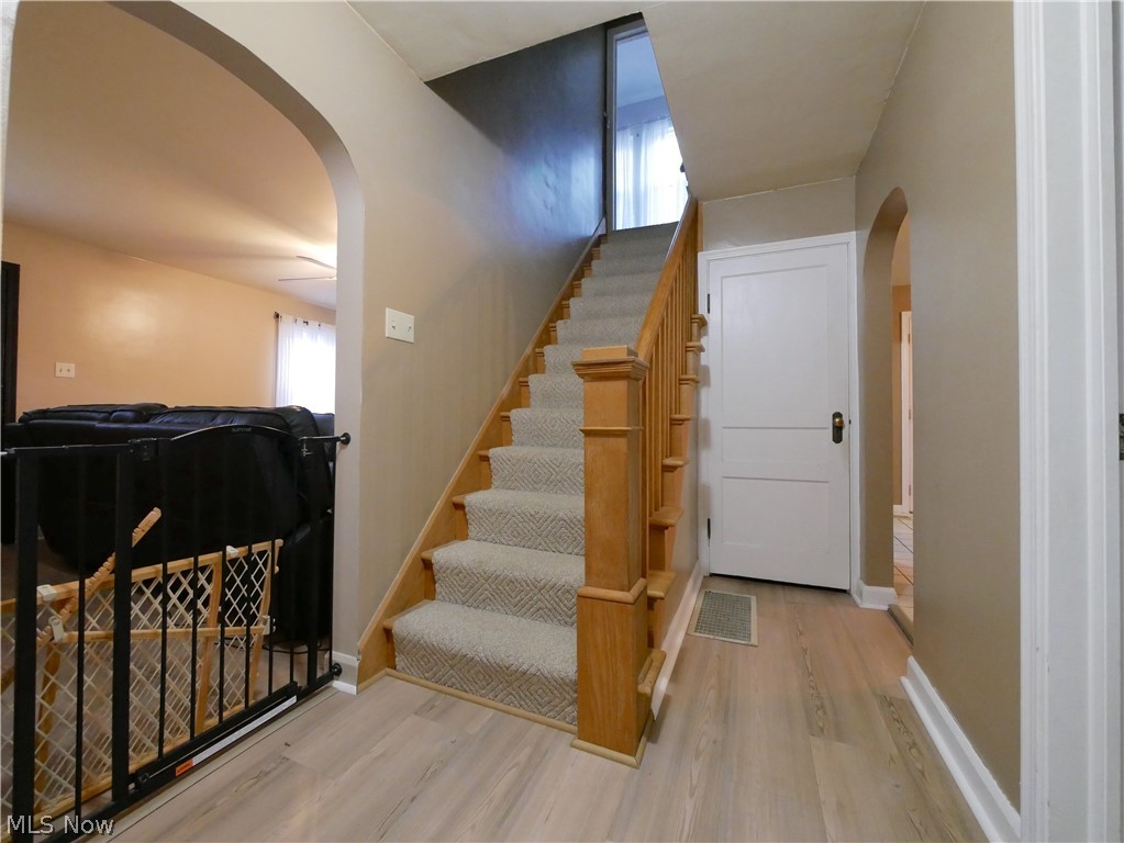 72622 Colerain Road Dillonvale, OH 43917 - Photo 8 of 17 Wood-finish flooring, staircase with carpeted treads and wood handrail, white interior door with brass hardware, and arched entryway