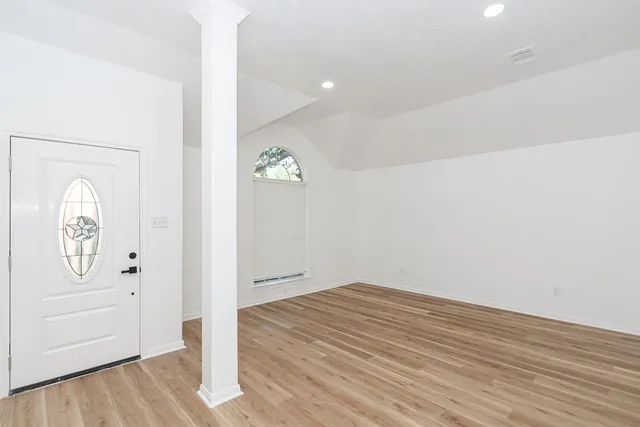 an empty room with wooden floor cabinet and mirror