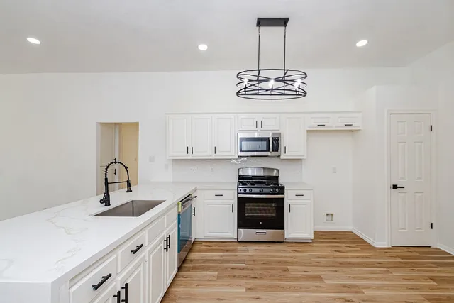 a kitchen with stainless steel appliances a sink stove and cabinets