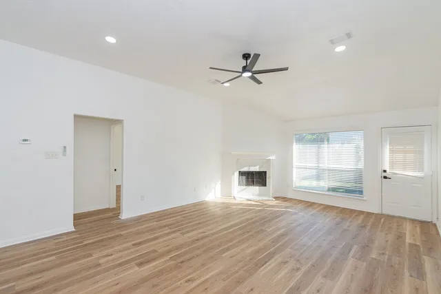 a view of empty room with wooden floor and window