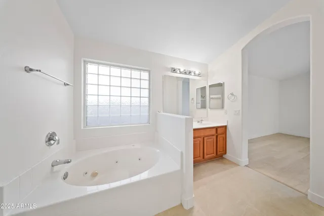 a spacious bathroom with a tub sink and mirror