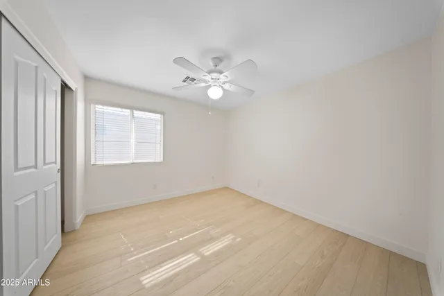 an empty room with windows and ceiling fan