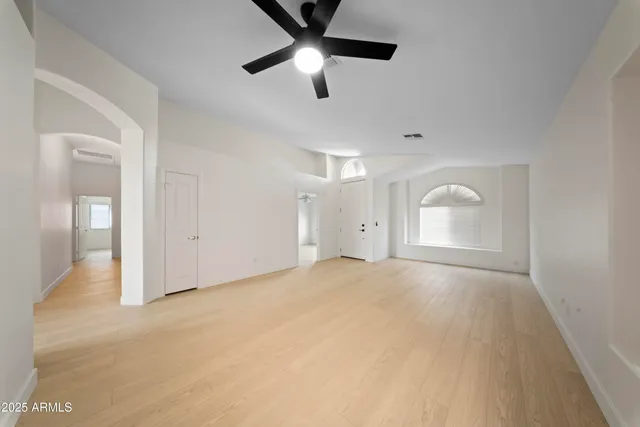 a view of an empty room and chandelier fan