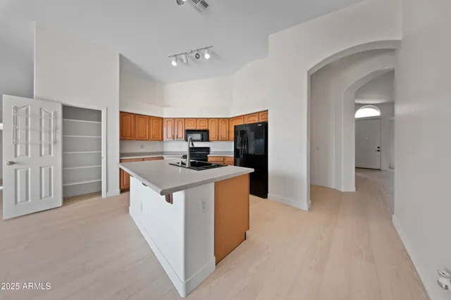 a kitchen with stainless steel appliances kitchen island granite countertop a refrigerator and a sink