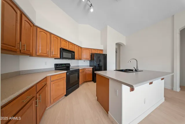 a kitchen with stainless steel appliances granite countertop a stove top oven a sink dishwasher and a refrigerator with wooden cabinets