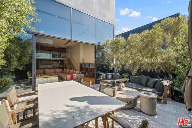 a roof deck with table and chairs and potted plants
