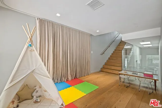 a view of an empty room with wooden floor and stairs