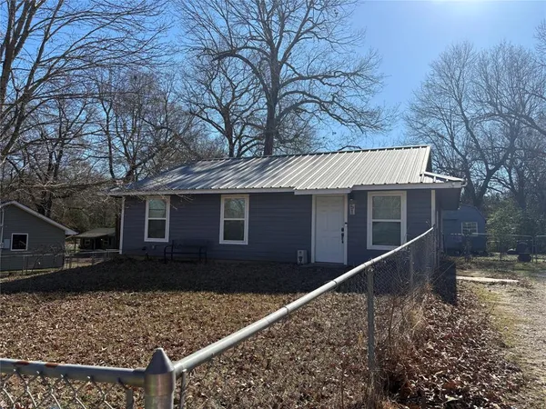 a view of a house with a large tree next to a yard