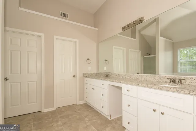 a bathroom with a granite countertop sink two mirror and a
