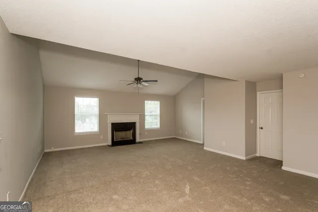 an empty room with windows and fireplace