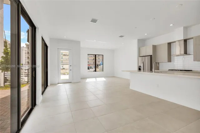 a view of an empty room with kitchen and a window
