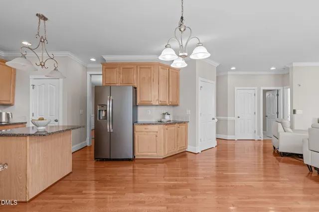 a kitchen with stainless steel appliances granite countertop a refrigerator a sink dishwasher a stove and white cabinets with wooden floor