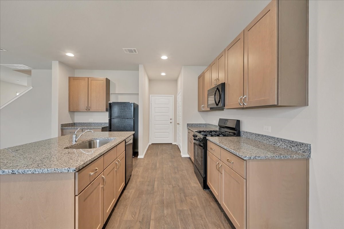 116 Honeybee Lane Elgin, TX 78621 - Photo 12 of 37 a kitchen with stainless steel appliances granite countertop a sink stove and cabinets