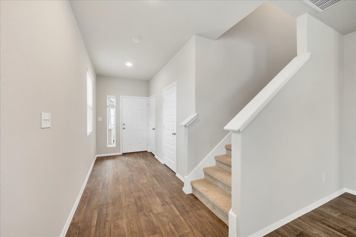 116 Honeybee Lane Elgin, TX 78621 - Photo 7 of 37 a view of a hallway with wooden floor and staircase
