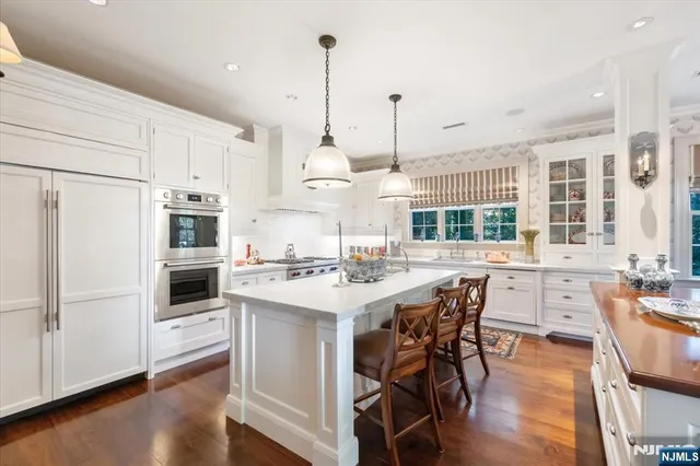 a kitchen with stainless steel appliances kitchen island granite countertop a stove a sink a dining table and chairs with wooden floor