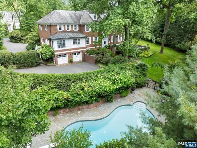 a view of a house with a yard plants and large trees