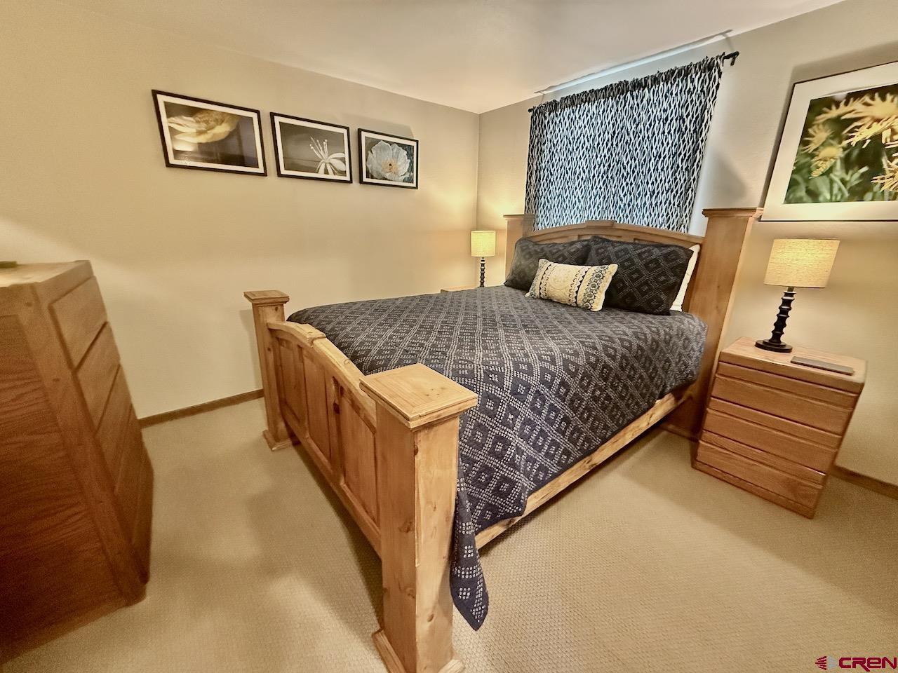 11 Snowmass Road, Unit 337 Crested Butte, CO 81225 - Photo 28 of 35 a bed sitting in a bedroom next to a lamp with wooden floor